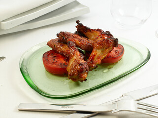 Pollo rebozado con tomate asado sobre plato de cristal verde en fondo blanco. Battered chicken with roasted tomato on green glass plate on white background.
