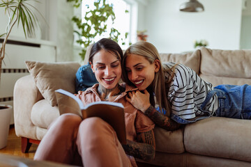 Obraz premium Lesbian couple reading book at home