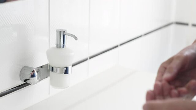 Man hand washing with liquid soap over bathroom sink, close-up of male hands using antibacterial sanitizer, coronavirus COVID-19 prevention, hygiene