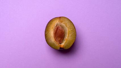 half ripe plum on a pink background