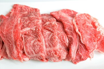 皿に載せた牛肉の薄切り、スライスした和牛肉、すき焼き用の牛肉、白背景