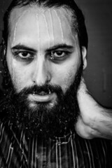 black and white portrait of a young bearded man who refreshes himself by pouring water on his head and running it on his face