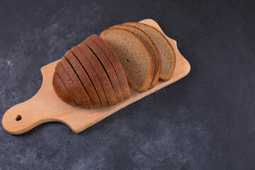 Sliced rye bread on a cuttig Board and a black table.