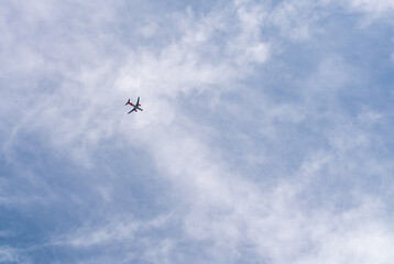 Airplane in a cloudy sky flies from left to right. Passenger or cargo transportation. There is space to add text. 