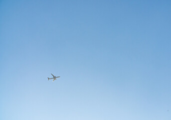 Airplane in a clear blue sky flies from left to right. Passenger or cargo transportation. There is space to add text. 