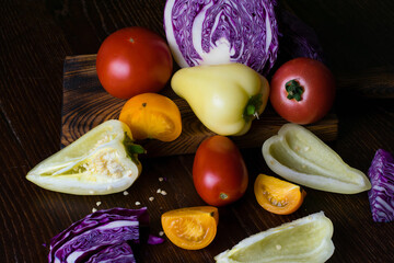 Vegetables on a dark countertop. Chopped bell peppers, cabbage and tomatoes, flat lay