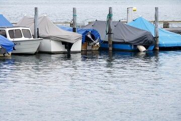 Sailing boats arranged in row covered for winter season and with lowered sails. The vessels anchor...