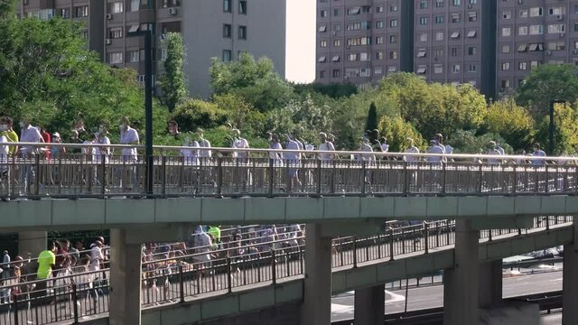 Pedestrians walks on overpass. Hot sunny day during the pandemic outdoors. People walking with covid mask. Timelapse version with echo effect.. The crowds of people walking