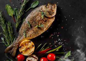 Roasted fish, served on black tray. overhead, horizontal, copy space - image