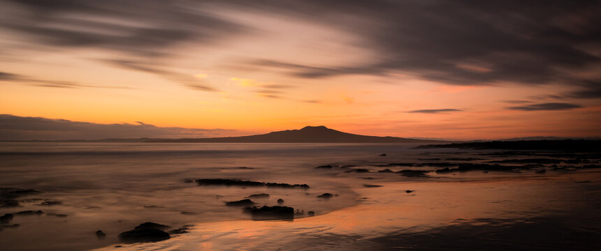 Long exposure image of Milford beach at sunrise with Rangitoto Island in the background, Auckland