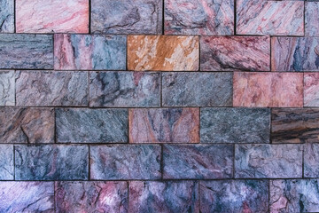 Decorative wall cladding with multi-colored granite tiles. Background from colored natural stones. Decorative cladding with multi-colored natural stone tiles. Wall decoration with colored granite.