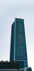 Obraz premium Central Jakarta, Indonesia - March 21th, 2021: A tall green building under a clear sky with fluffy clouds.