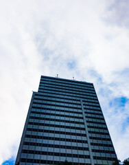 Fototapeta na wymiar Central Jakarta, Indonesia - March 21th, 2021: A tall blue building under a clear sky with fluffy clouds.