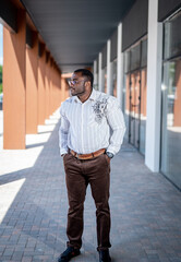 Smart handsome man keeping his arms at the pockets and looking away. Urban street fashionable businessman. Full length view