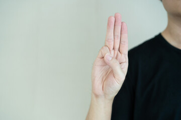 Unrecognizable Thai young man showing a three finger sign which is the sign use in anti Thai government protester in 2021.