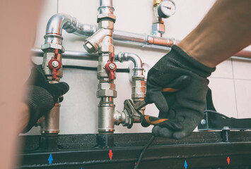 Plumber screwing nut of pipe in the heating system in the boiler room