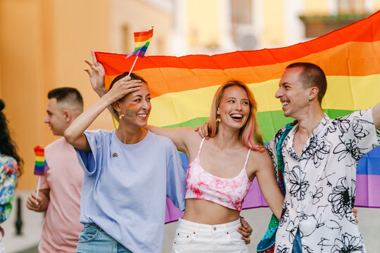 Multiracial men and women walking with rainbow flags during pride parade