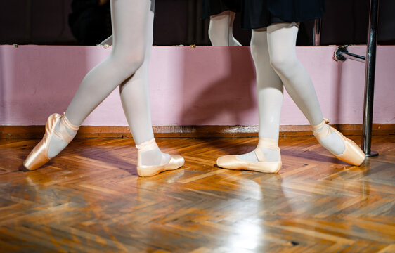 Legs of young ballerinas. Rehearse in the ballet class. Dressed in white pantyhose and ballet shoes. Pointe shoes concept