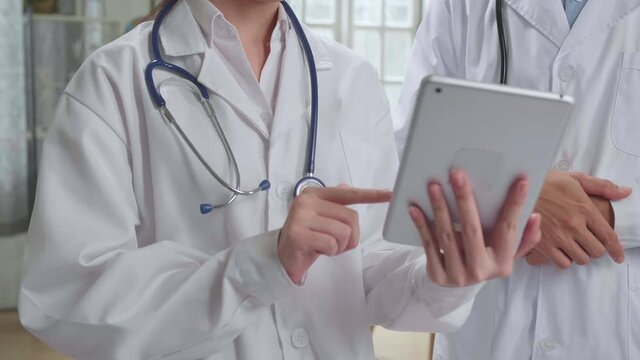 Doctor'S Office: Asian Physician Talks With Professional Nurse, Using Tablet Computer. Medical Health Care Specialists Discuss Test Results, Prescription Medicine, Patient Treatment
