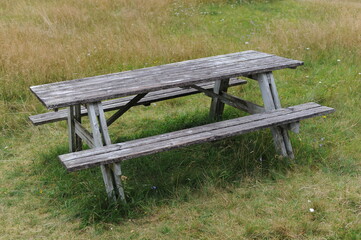 Wooden table and benches for outdoor dining and picnic on a grass field at the camping