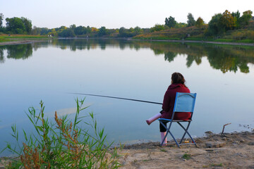 Fototapeta na wymiar The fisherwoman is expecting a bite. Fishing. The Woman is fishing. Fisherwoman on the bank of the river. 