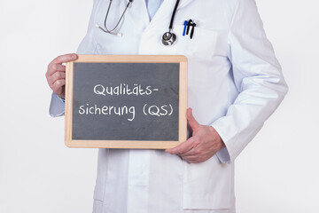 Arzt mit einer Tafel Qualitätssicherung QS in der Arztpraxis oder Klinik