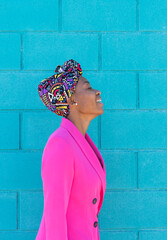 Retrato de perfil de chica africana con pañuelo sonriendo, en fondo azul.