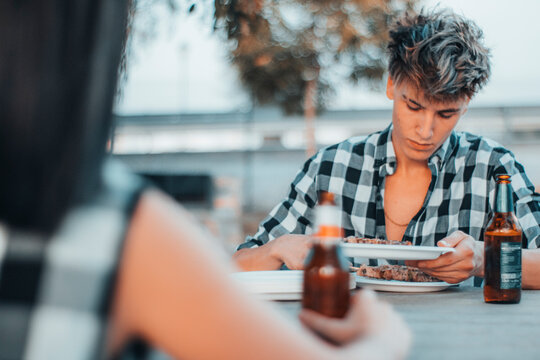 Chaval joven de camisa de cuadros en una fiesta de parrillas repartiendo los platos a amigos