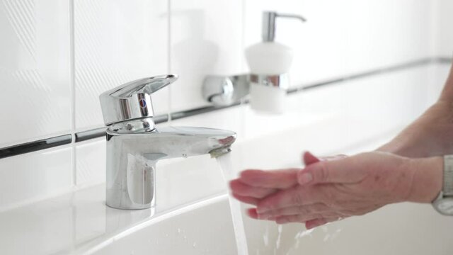 Hand washing with liquid soap, close-up of female hands rinsing with water over bathroom sink, woman using antibacterial sanitizer, coronavirus COVID-19 prevention, hygiene