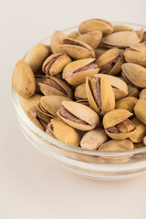 Pistachios in a glass bowl on a light background.