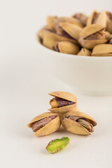 Pistachios close-up on a light background and in a white bowl.