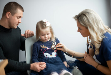 Father with girl being examined by female pediatrician in clinic
