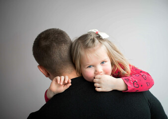 Emotional portrait of father and daughter on a gray studio background
