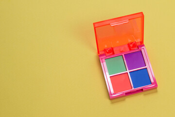 Purple, green, orange and blue eye shadow palette on a green background. Make up. Neon colours.