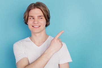 Happy guy isolated showing pointing promotion with finger blue empty space background