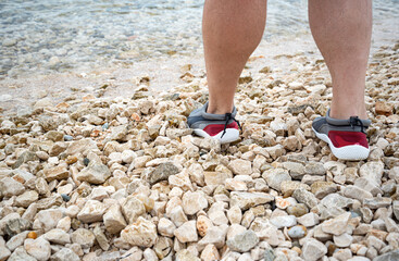 Men's feet in swimming slippers. Rocky beach.