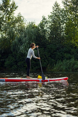 Young Caucasian woman, sportsman, tourist standing on paddle board, SUP, practicing alone. Active life, sport, leisure activity concept