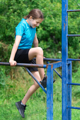 teenage girl exercising outdoors, sports ground in the yard, she does push-ups at the bars, healthy lifestyle