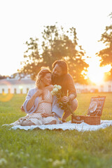 Beautiful pregnant young couple having a picnic at sunset