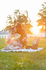 Handsome man kissing his pregnant wife at a picnic