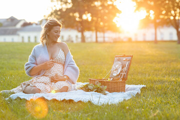 Beautiful pregnant woman sitting at a picnic