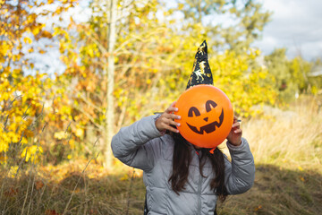 Obraz premium Halloween kids. Little girl with jack o' lantern in witch hat with pumpkin. Toddler kid in witch costume playing in autumn park.