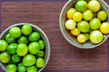 Husked ripe tomatillos (Physalis) in two ceramic bowls top view.
