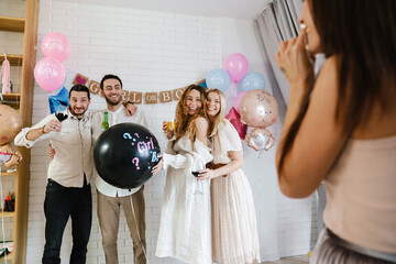 Group of happy friends at a gender reveal baby shower - obrazy, fototapety, plakaty