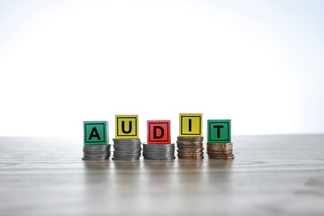 AUDIT written on the colorful blocks on the stacked coins
