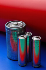 several multi-colored batteries on a blue-red background. close-up.