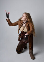 Full length portrait of beautiful young woman with long red hair, wearing steampunk inspired...