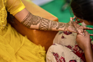 View of a woman drawing traditional Henna Mehandi body art on a hand