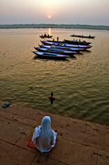 A devotee sat in a bank of river Ganges in Varanasi in the   morning. 