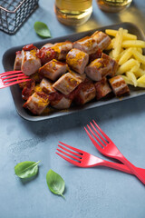 Currywurst or german traditional sausages served with tomato sauce and curry, vertical shot on a grey concrete background